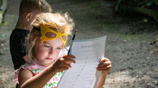 A young girl with pencil in hand looking intently at an activity trail sheet
